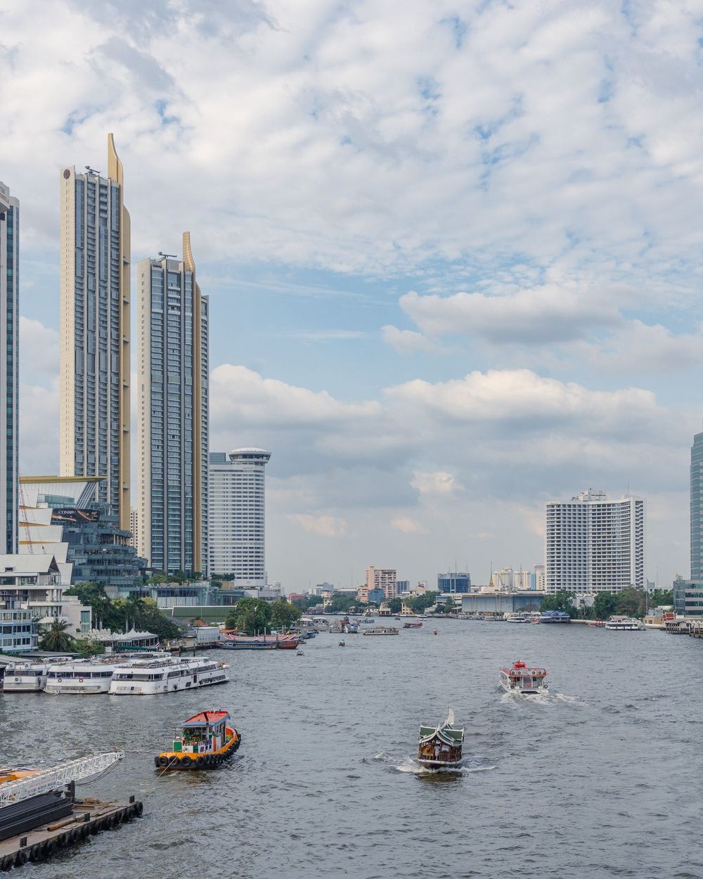 Long-tail boats on the Chao Phraya river below the Bangkok skyline