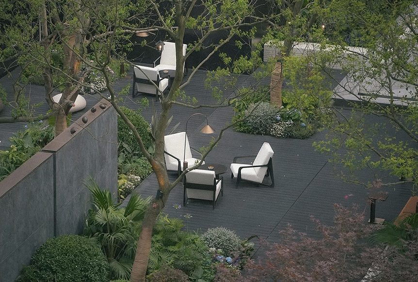 Garden chairs among mature planting behind the gate